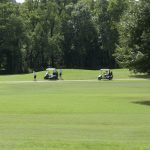 Bella Vista Country Club Golf Course and Clubhouse along Highways 49/71 in Northwest Arkansas. Three female unknown golfers with golf carts in the distance.